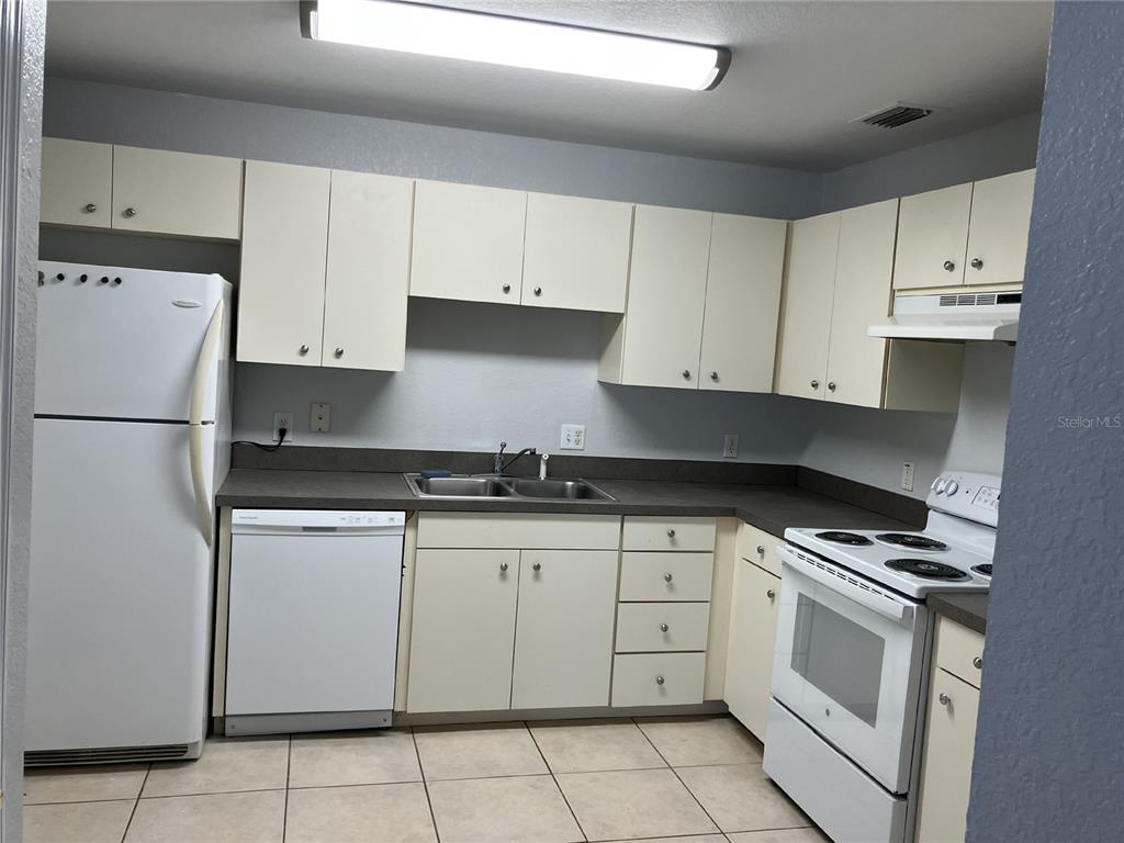 A kitchen with white appliances, light-colored cabinets, and tile flooring — 5527 GAUR LANE, LAKELAND, FL