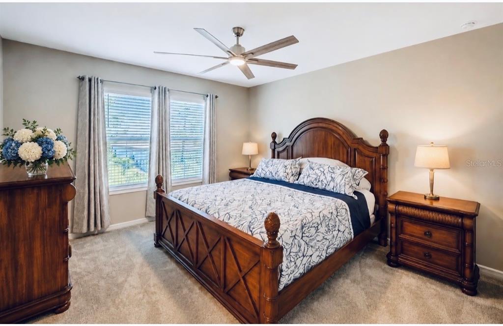 A bedroom features a wooden bed frame, two nightstands, a ceiling fan, and window curtains — 8344 SW 54TH LOOP, OCALA, FL