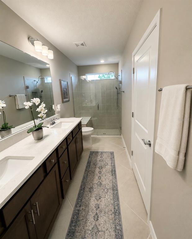 A bathroom features a double vanity with dark cabinets, a walk-in shower, and tile flooring — 8344 SW 54TH LOOP, OCALA, FL