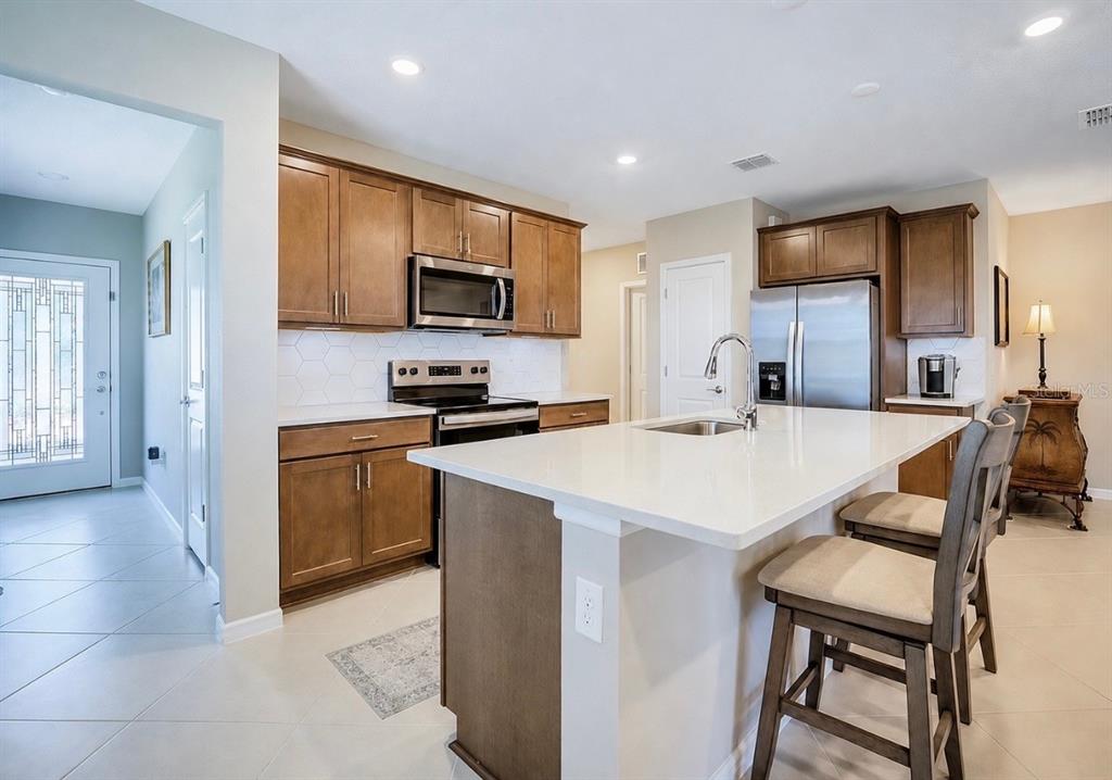 A kitchen features wood cabinets, white countertops, stainless steel appliances, and a central island — 8344 SW 54TH LOOP, OCALA, FL