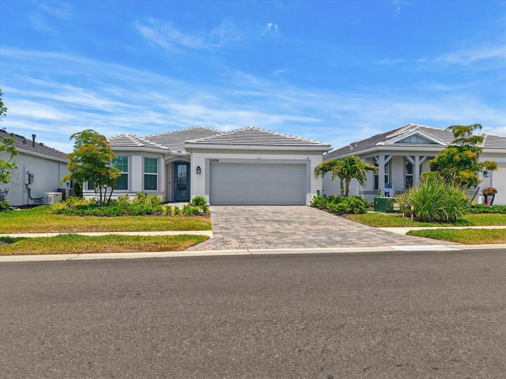 A single-story suburban house features a gray tiled roof, a paved driveway, and a garage — 10408 SEA BREEZE RIDGE DRIVE, ENGLEWOOD, FL