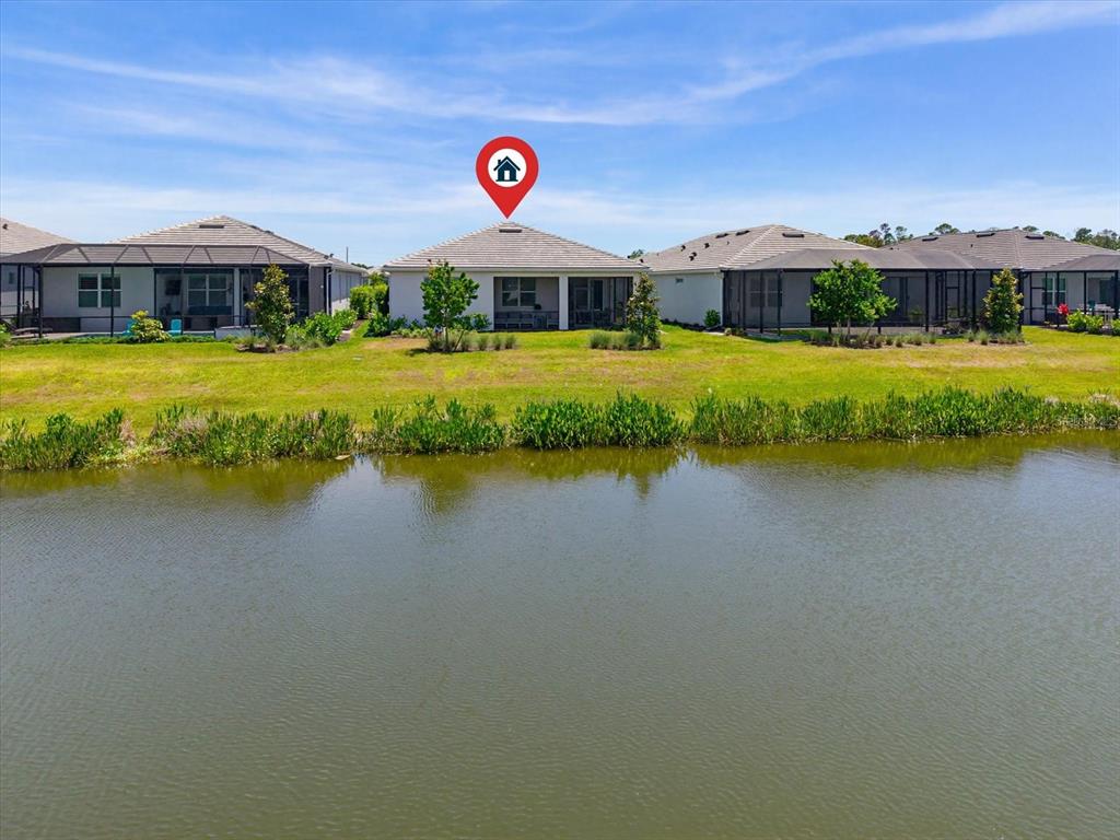 A rear view of a house with a screened lanai overlooking a pond — 10408 SEA BREEZE RIDGE DRIVE, ENGLEWOOD, FL