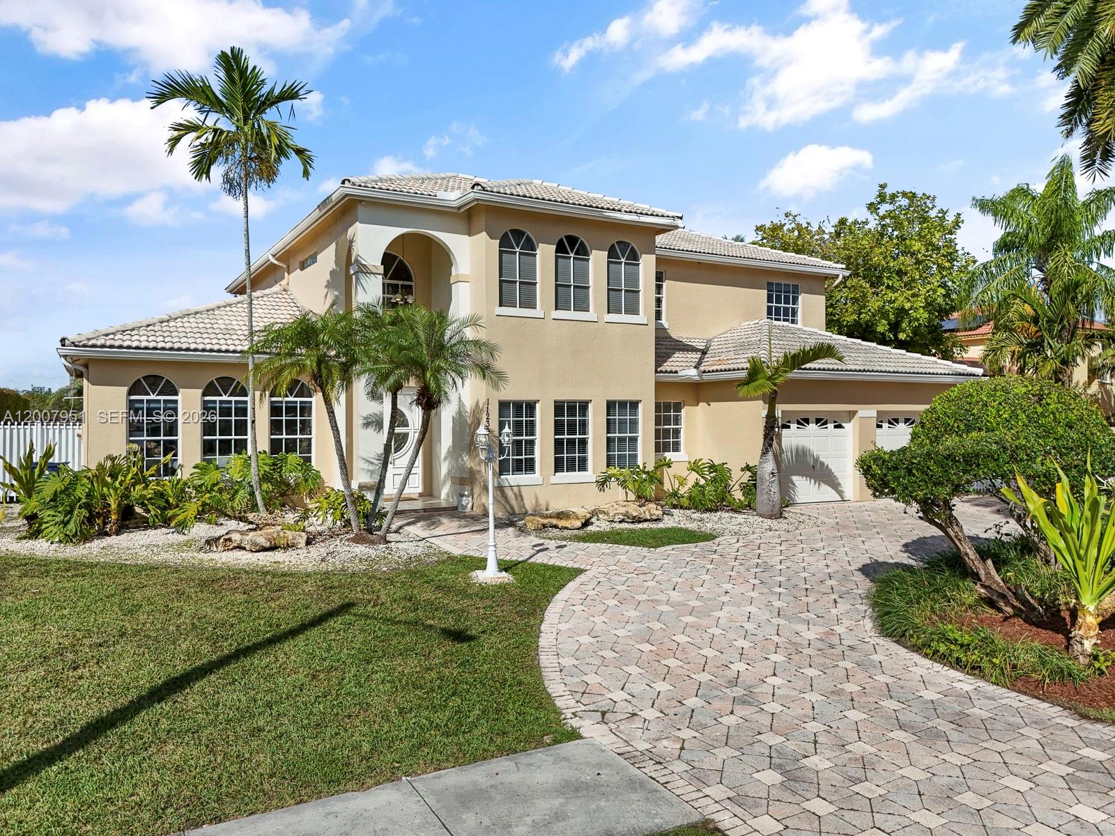 A two-story beige house with a tiled roof, arched windows, and a paved circular driveway — 11230 SW 156th Ave, Miami FL 33196, MIAMI, FL
