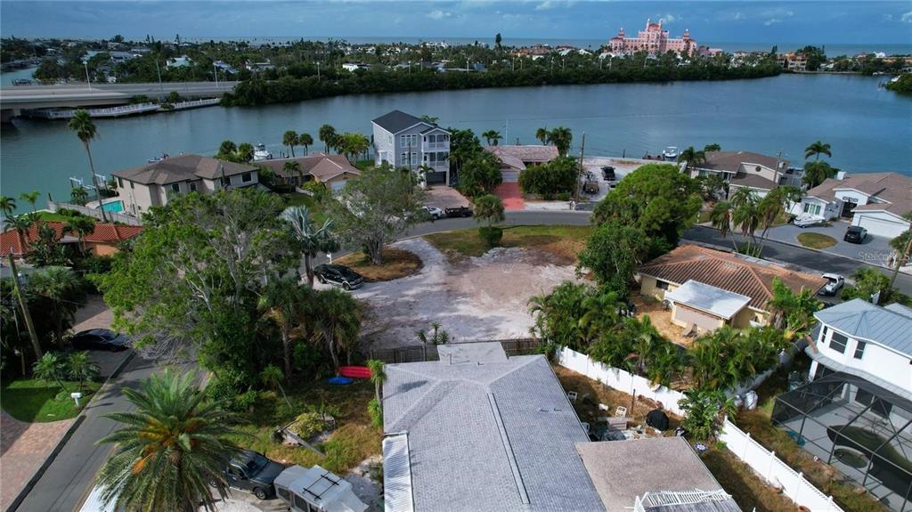 An aerial view shows a vacant residential lot surrounded by houses near a coastal waterway — 3615 BELLE VISTA DRIVE E, ST PETE BEACH, FL
