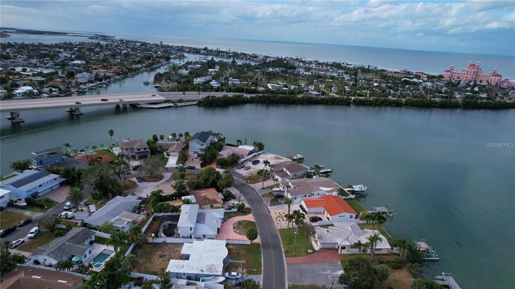 An aerial view shows waterfront homes along a curved road near a bridge and ocean — 3615 BELLE VISTA DRIVE E, ST PETE BEACH, FL