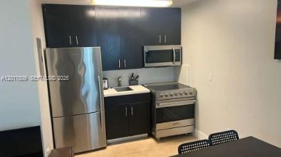 A compact kitchen features dark cabinets, stainless steel appliances, and a light-colored countertop — MIAMI BEACH, FL