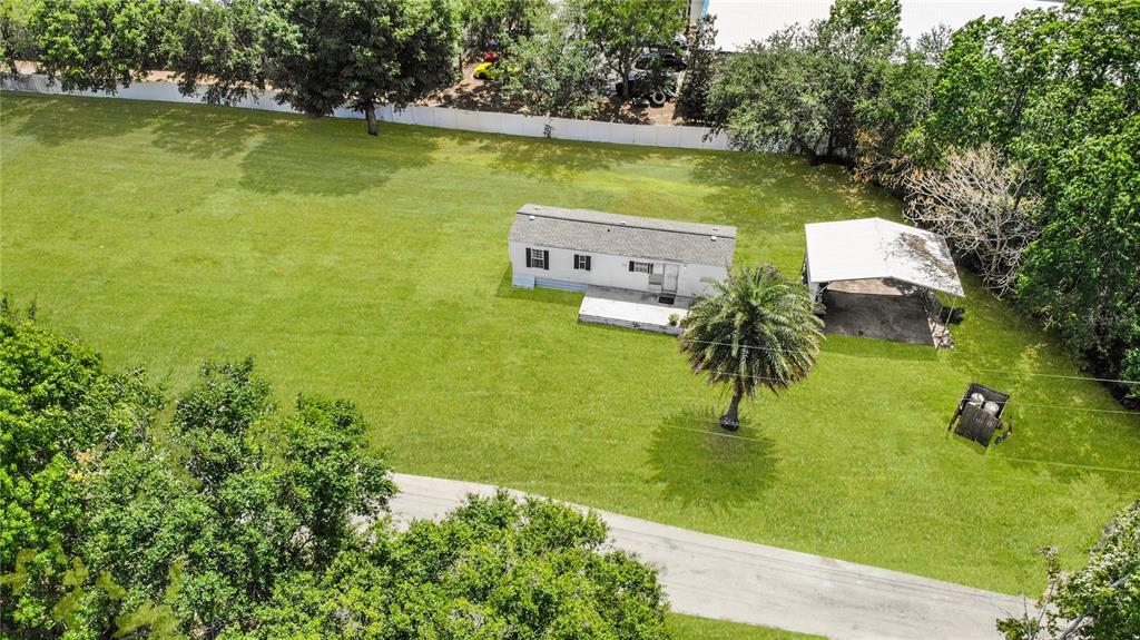 An aerial view shows a small house with a carport on a large, grassy lot — 8292 DAKOTA DRIVE, ORLANDO, FL