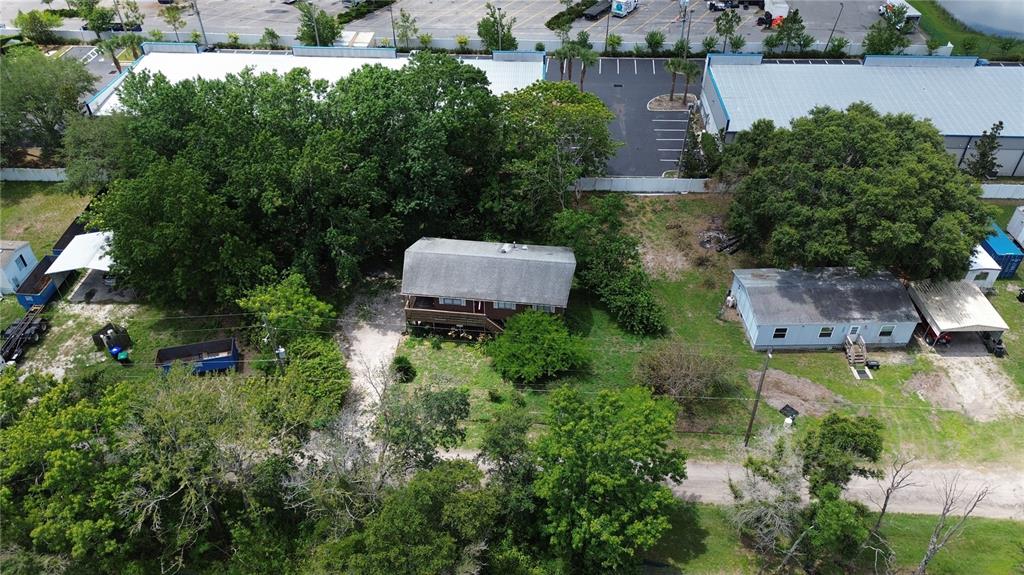 An aerial view shows two houses on a wooded lot near a large commercial parking area — 8292 DAKOTA DRIVE, ORLANDO, FL