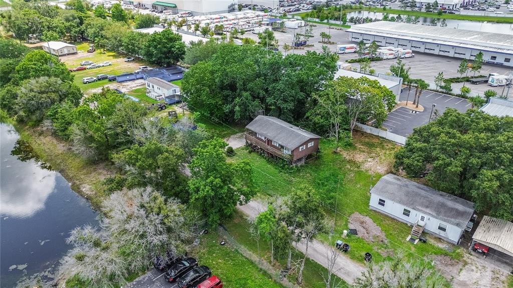 An aerial view shows two houses situated on a wooded lot next to a canal — 8292 DAKOTA DRIVE, ORLANDO, FL