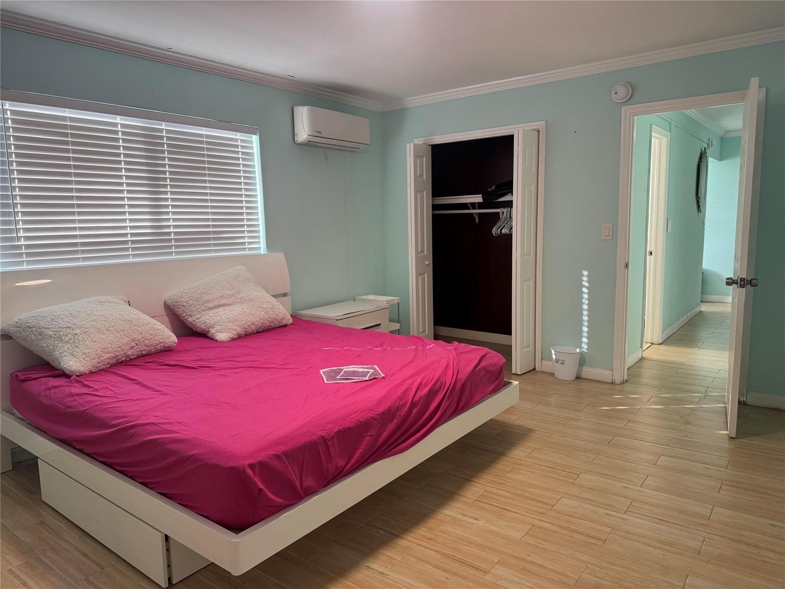 A bedroom features light blue walls, a white platform bed with pink bedding, and wood-look flooring — 323 Monroe Street # 2, Hollywood FL 33019, HOLLYWOOD, FL