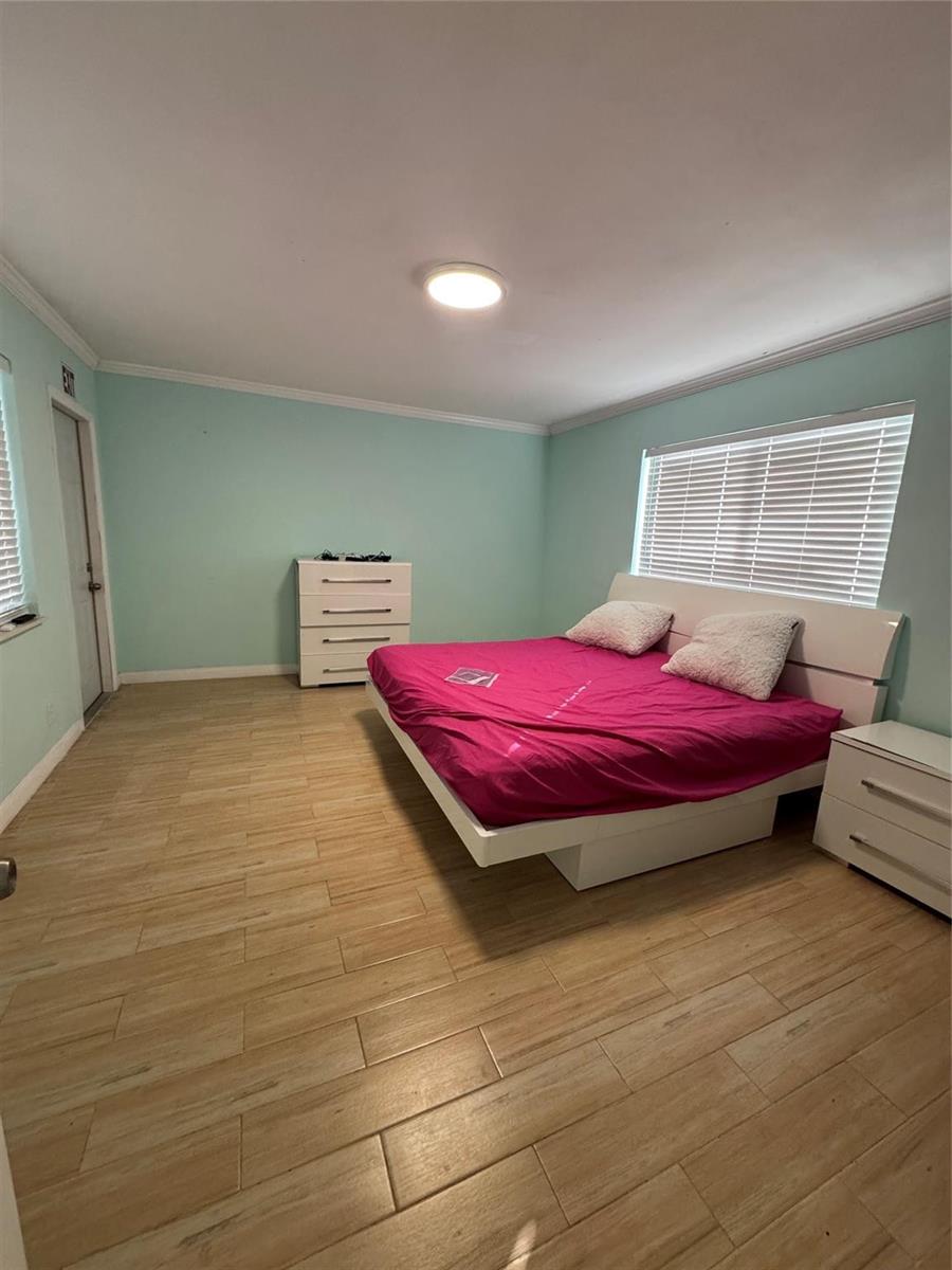 A bedroom with light blue walls, wood-look tile flooring, and a white platform bed — 323 Monroe Street # 2, Hollywood FL 33019, HOLLYWOOD, FL