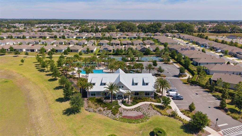 An aerial view shows a community clubhouse with a swimming pool and tennis courts — 5092 STOKES WAY, WILDWOOD, FL