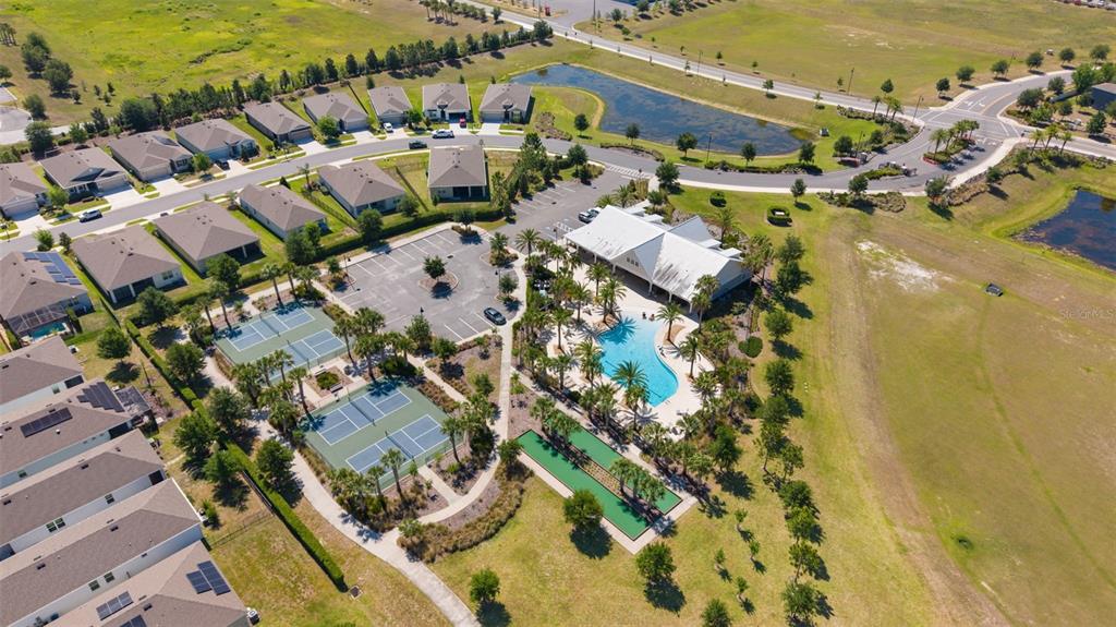 An aerial view shows a community clubhouse with a pool, tennis courts, and nearby houses — 5092 STOKES WAY, WILDWOOD, FL