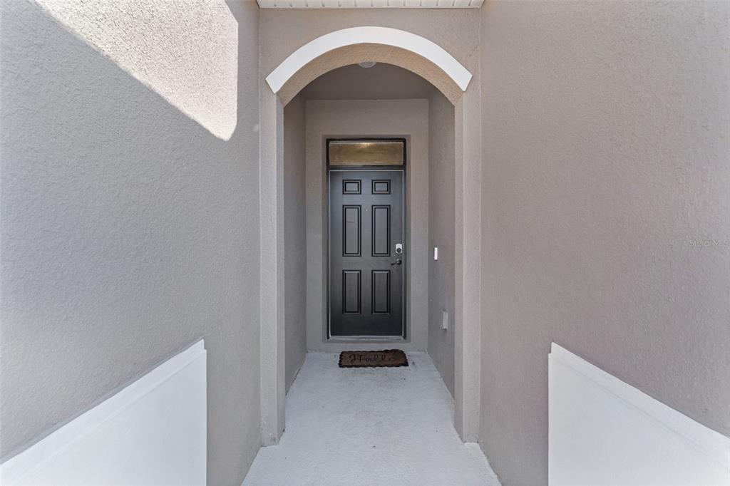 A recessed entryway features a dark front door with a transom window under an arch — 5092 STOKES WAY, WILDWOOD, FL