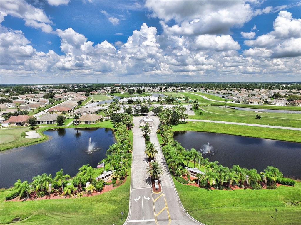 An aerial view shows a gated community entrance with fountains, palm trees, and surrounding homes — 24191 BUCKINGHAM WAY, PUNTA GORDA, FL