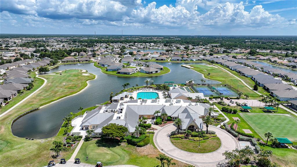 An aerial view shows a community clubhouse with a pool, tennis courts, and surrounding homes — 24191 BUCKINGHAM WAY, PUNTA GORDA, FL