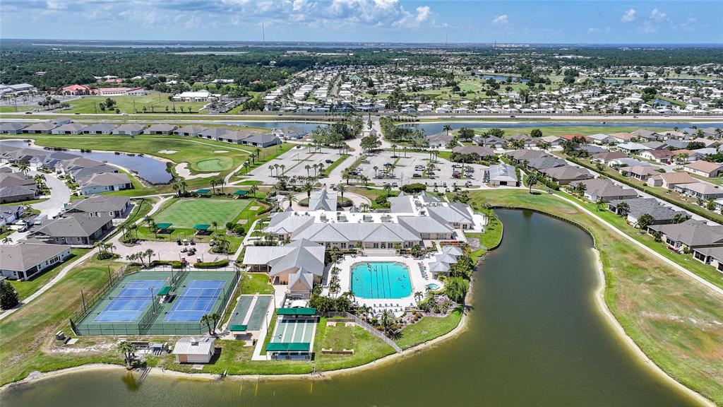 An aerial view shows a community clubhouse with a pool, tennis courts, and surrounding homes — 24191 BUCKINGHAM WAY, PUNTA GORDA, FL