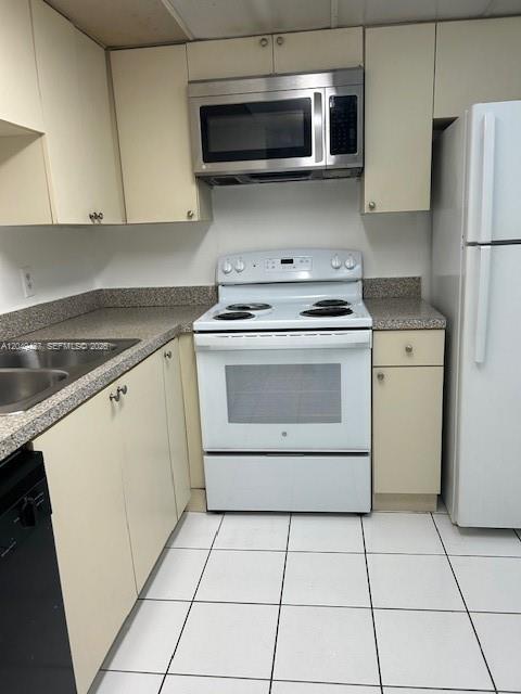 A kitchen features light-colored cabinets, a white stove, a stainless steel microwave, and white flooring — 2055 SW 122nd Ave # 101, Miami FL 33175, MIAMI, FL