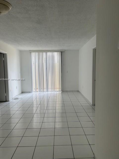 An empty room with white tile floors, a popcorn ceiling, and vertical window blinds — 2055 SW 122nd Ave # 101, Miami FL 33175, MIAMI, FL