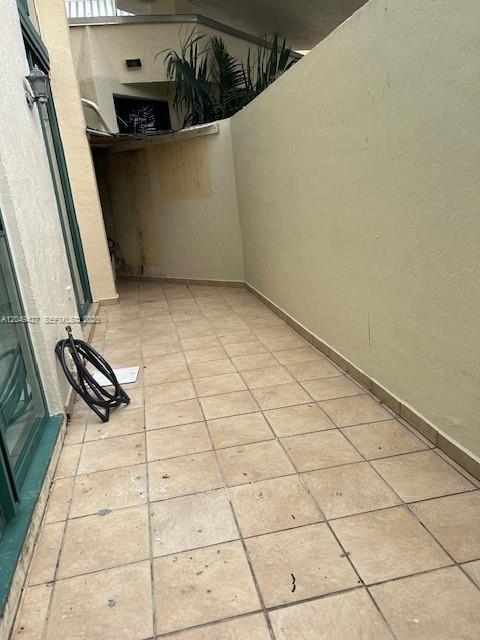 A tiled outdoor patio area features a wall-mounted hose and a partial view of greenery — 2055 SW 122nd Ave # 101, Miami FL 33175, MIAMI, FL