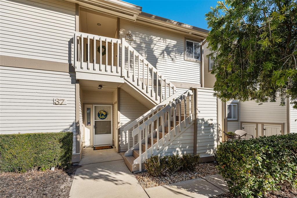 A two-story residential building exterior features light-colored siding, a staircase, and a front entrance — 39 MAGNOLIA DRIVE S UNIT 39, ORMOND BEACH, FL