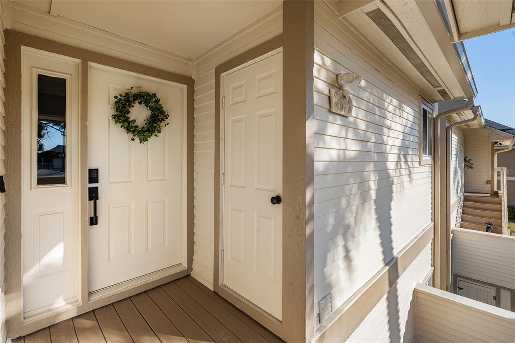 An exterior view of a home entrance with a white door, wreath, and wood-look flooring — 39 MAGNOLIA DRIVE S UNIT 39, ORMOND BEACH, FL