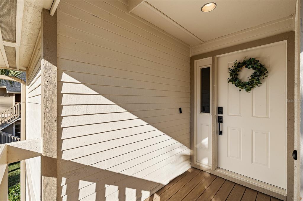 A white front door with a wreath stands on a wooden porch with siding — 39 MAGNOLIA DRIVE S UNIT 39, ORMOND BEACH, FL