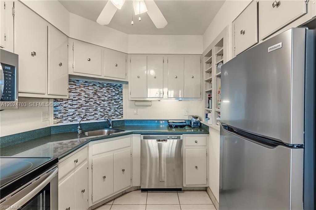 A kitchen features white cabinets, a green countertop, stainless steel appliances, and a mosaic backsplash — 5 Bluebill # 403, Naples FL 34108, NAPLES, FL