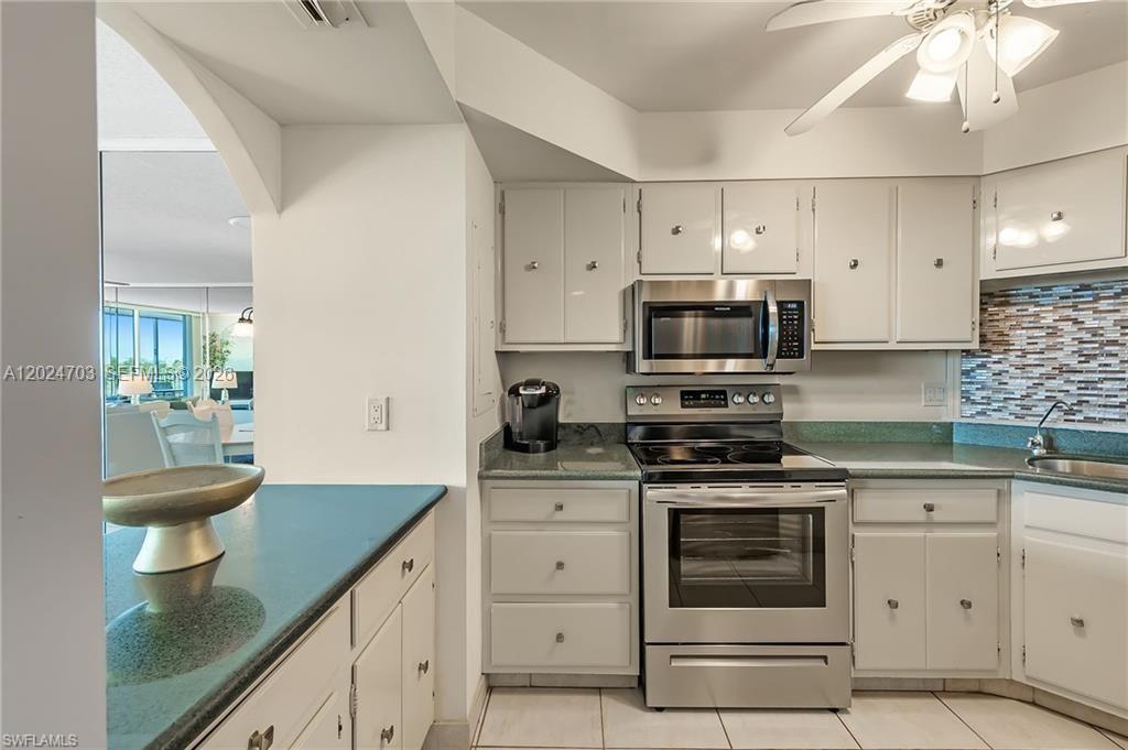 A kitchen features white cabinets, stainless steel appliances, and a green countertop — 5 Bluebill # 403, Naples FL 34108, NAPLES, FL