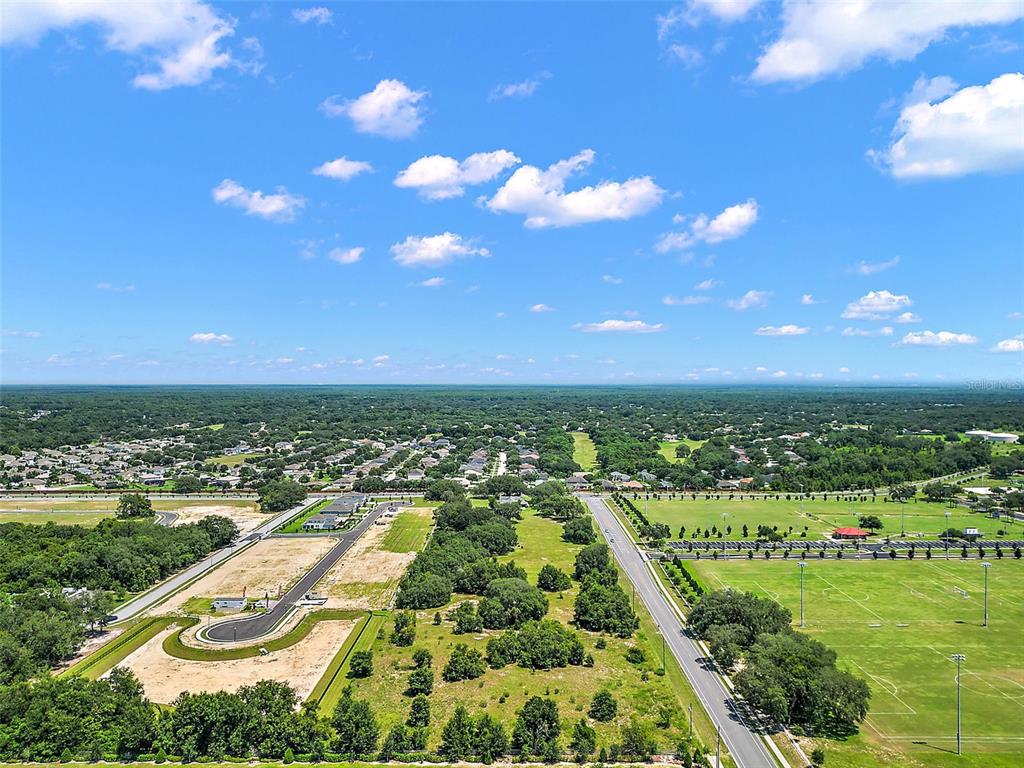 An aerial view shows a suburban neighborhood, a large grassy field, and a paved road — 2295 APPY LANE, APOPKA, FL