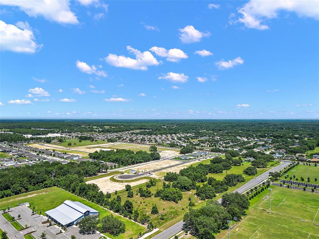 An aerial view shows a suburban landscape with a construction site, parking lot, and fields — 2295 APPY LANE, APOPKA, FL
