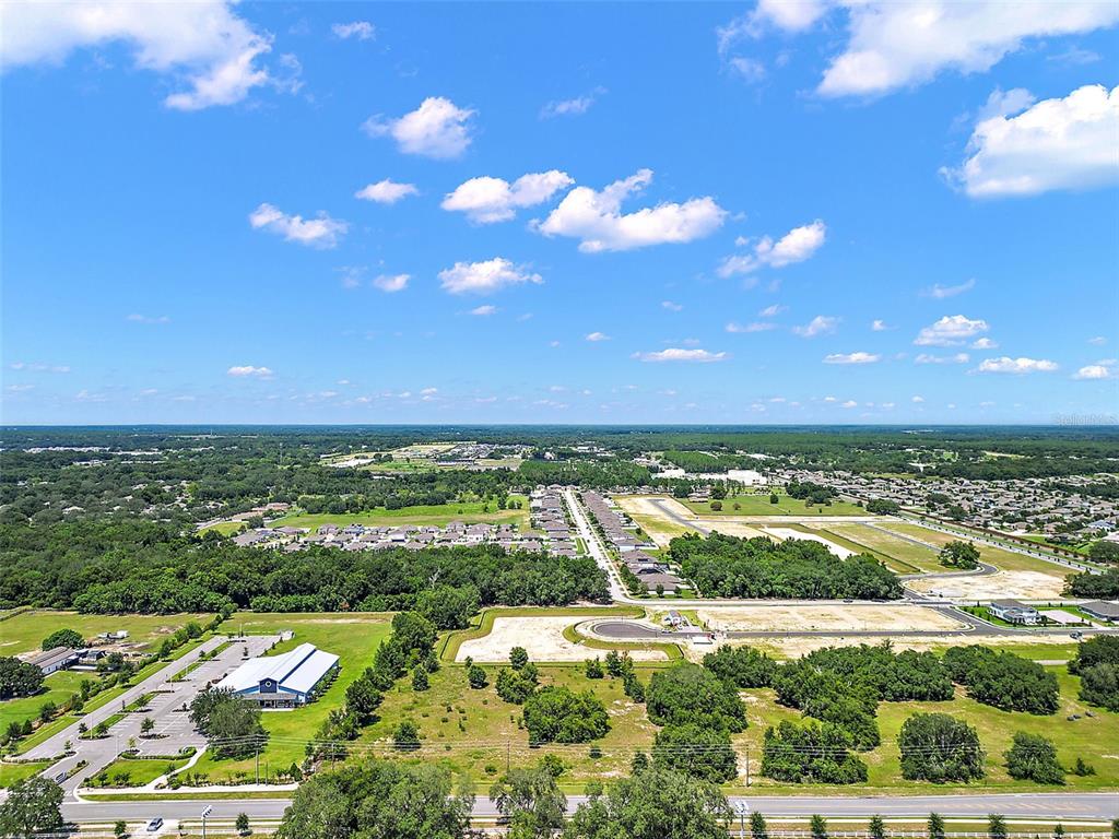 An aerial view shows a large parking lot, undeveloped land, and residential neighborhoods under a blue sky — 2295 APPY LANE, APOPKA, FL