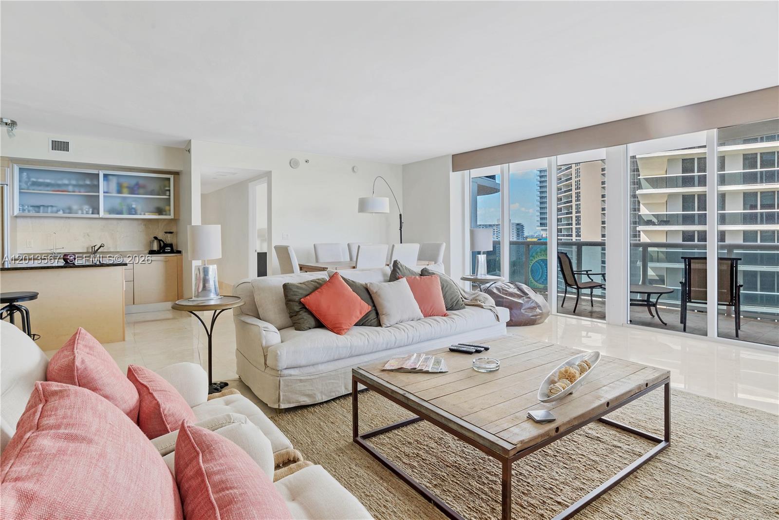 A bright living room features a wooden coffee table, white sofas, and a balcony view — 1850 S Ocean Dr # 1410, Hallandale Beach FL 33009, HALLANDALE BEACH, FL