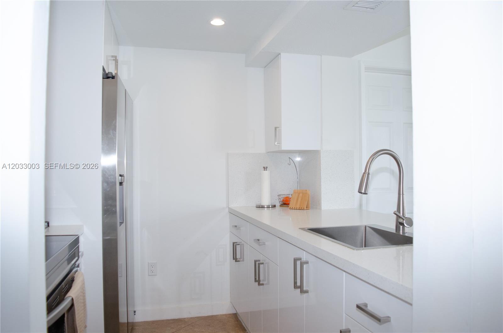 A modern kitchen features white cabinets, stainless steel appliances, and white quartz countertops — 6995 NW 186th St # E509, Hialeah FL 33015, HIALEAH, FL