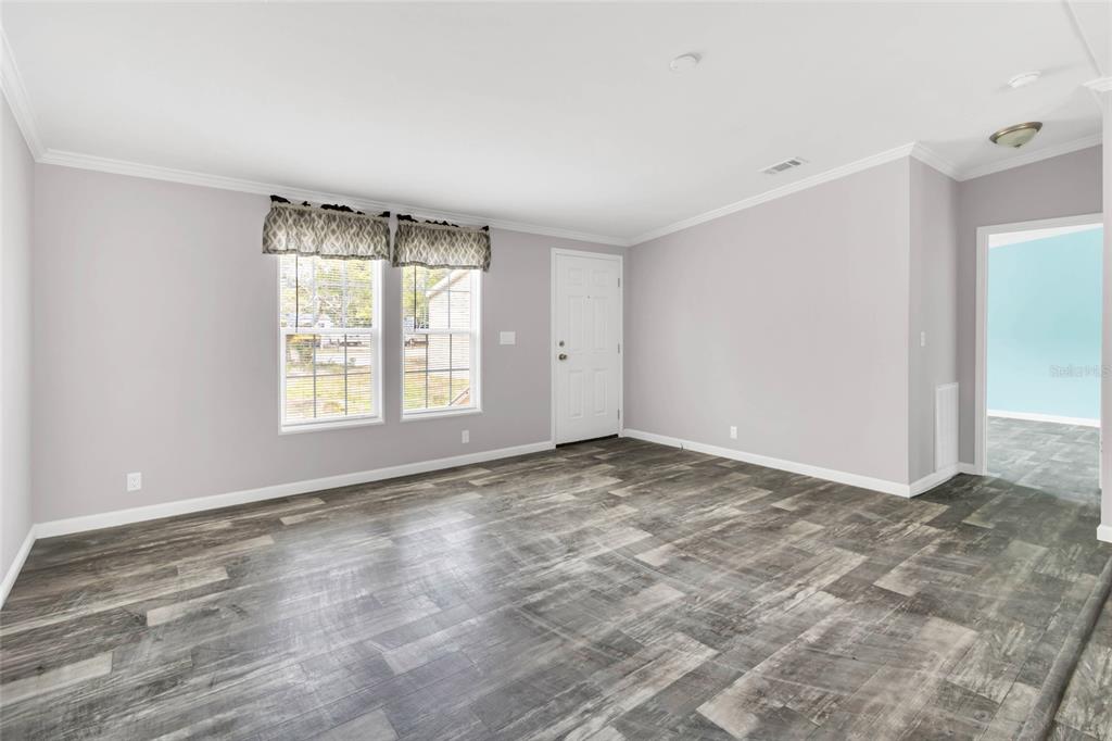 An empty room with light gray walls, wood-look vinyl flooring, and a white entry door — 3264 STEPHENS BOULEVARD, SPRING HILL, FL