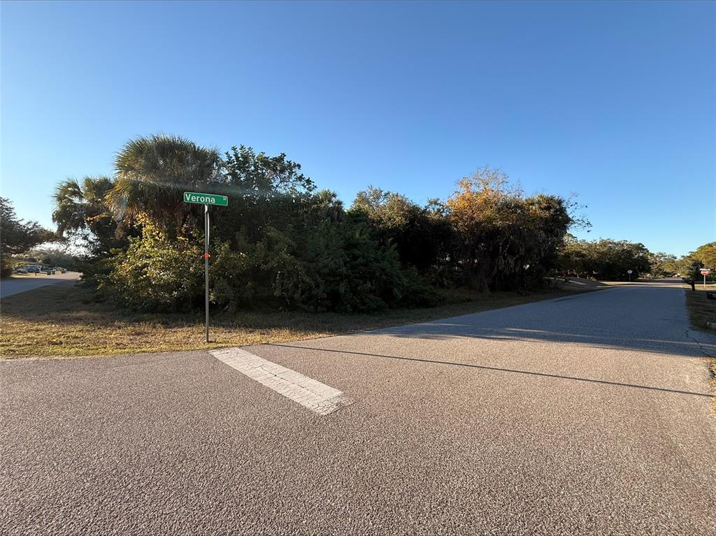 A street sign for Verona stands at a paved intersection surrounded by dense trees — 1100 BELMAR AVENUE, PORT CHARLOTTE, FL