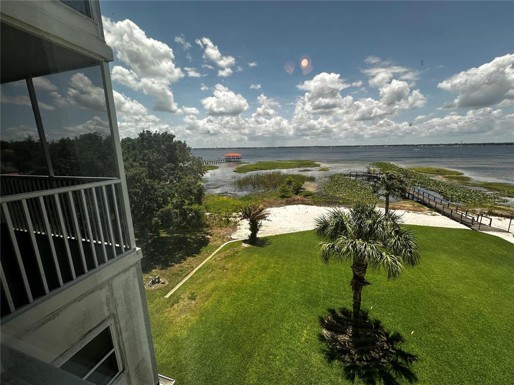 A view from a balcony overlooking a grassy lawn, palm trees, and a large lake — 2131 LAKEVIEW DRIVE UNIT 410, SEBRING, FL