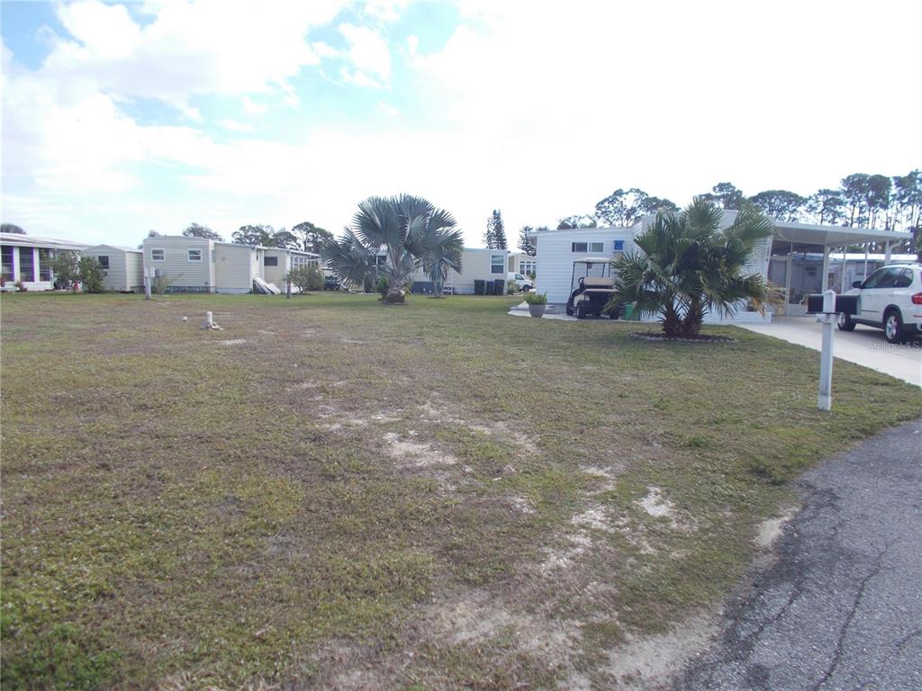 A grassy vacant lot sits between several manufactured homes in a residential community — 6466 KILOHEE COURT, NORTH PORT, FL