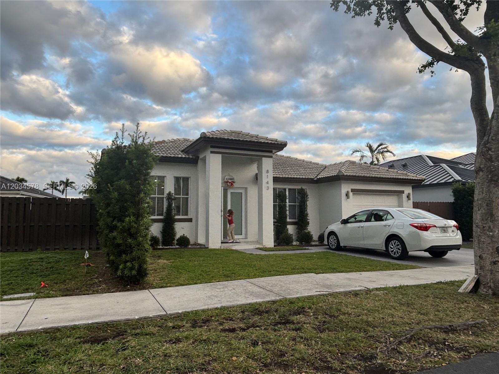 A white single-story house with a tiled roof and a car parked in the driveway — 8143 SW 162nd Path, Miami FL 33193, MIAMI, FL