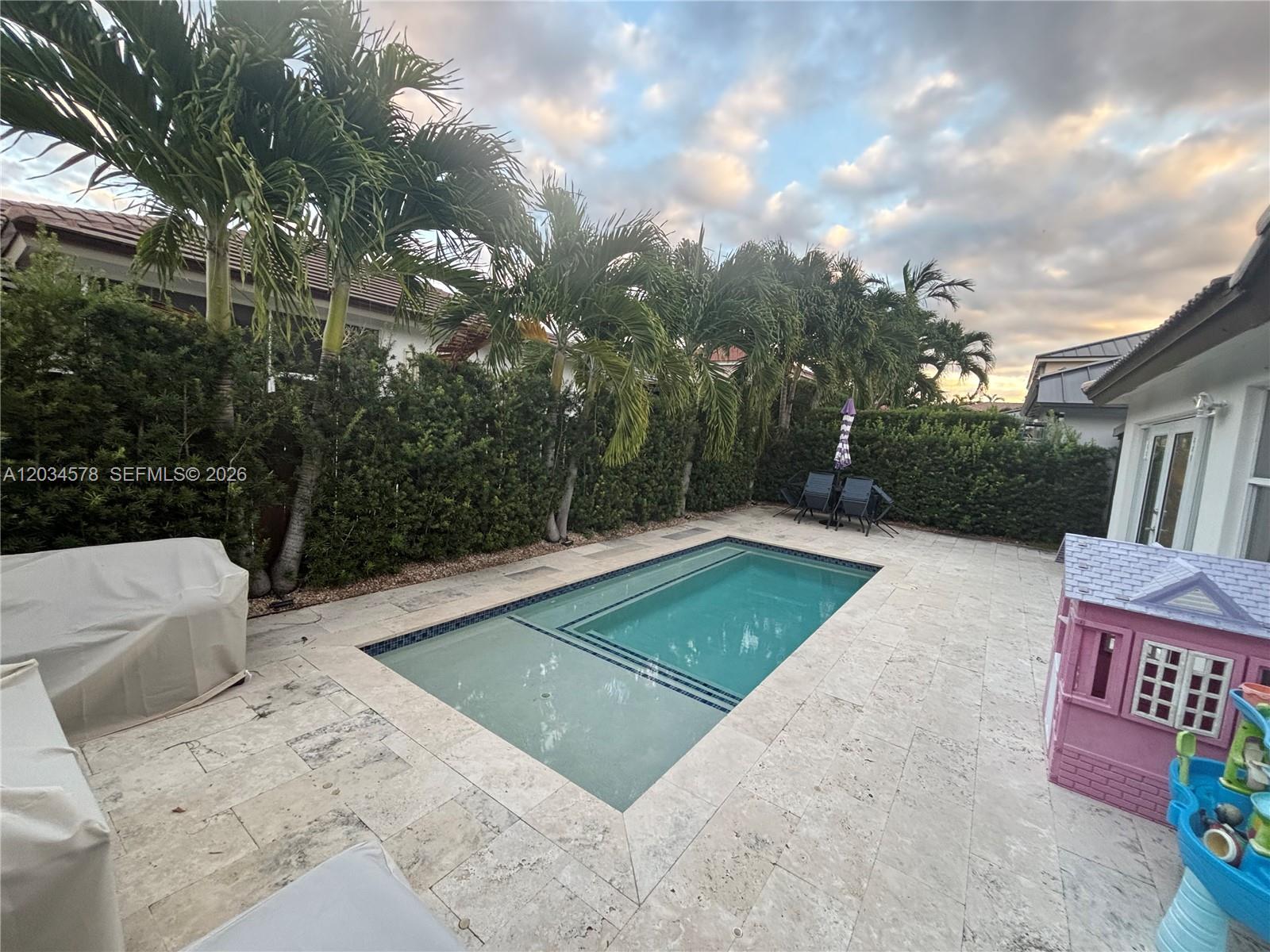 A backyard features a rectangular swimming pool, stone patio, palm trees, and a playhouse — 8143 SW 162nd Path, Miami FL 33193, MIAMI, FL