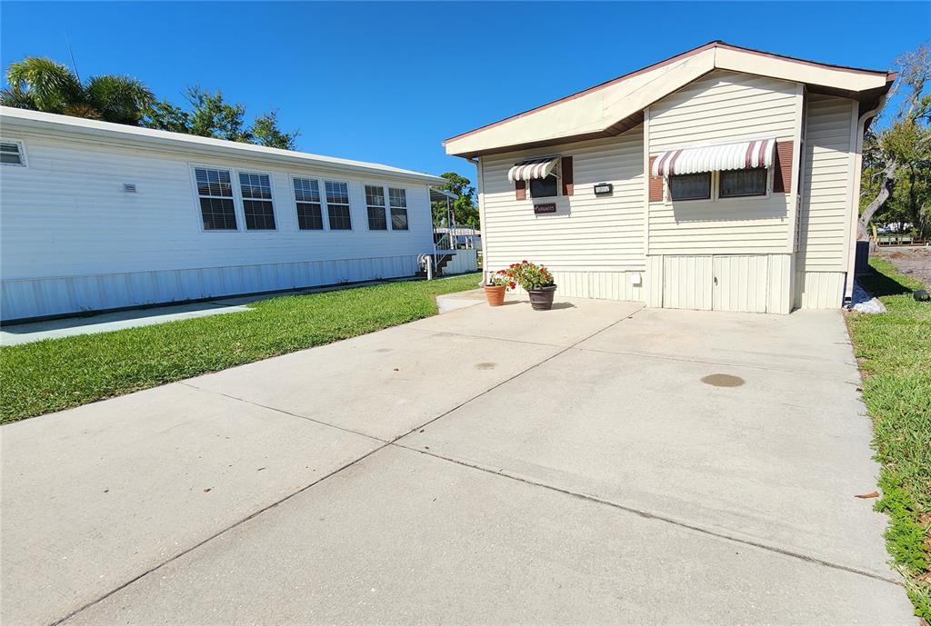 A concrete driveway leads to the front of a light-colored mobile home with siding — 3333 26TH AVENUE E UNIT 1292, BRADENTON, FL
