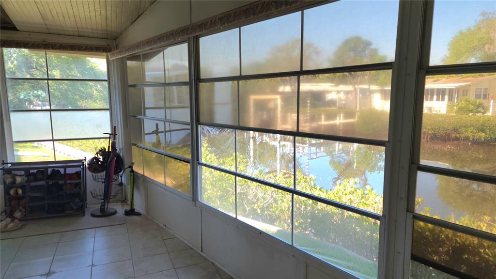 A sunroom with tiled floors and large windows overlooking a canal and neighboring homes — 3333 26TH AVENUE E UNIT 1292, BRADENTON, FL