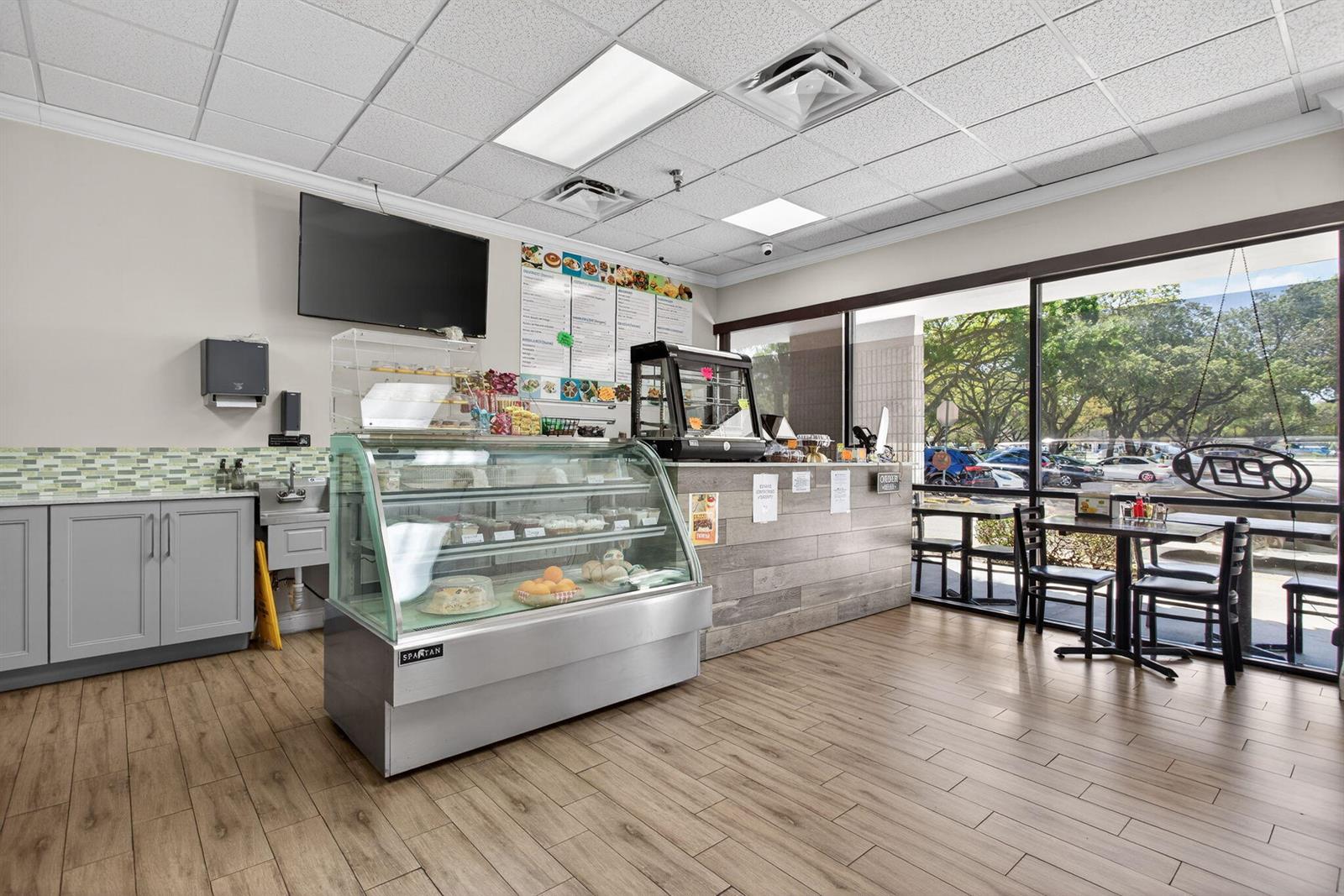 A commercial cafe interior features a glass display case, service counter, and large windows — Null W Null, Coconut Creek FL 33073, COCONUT CREEK, FL
