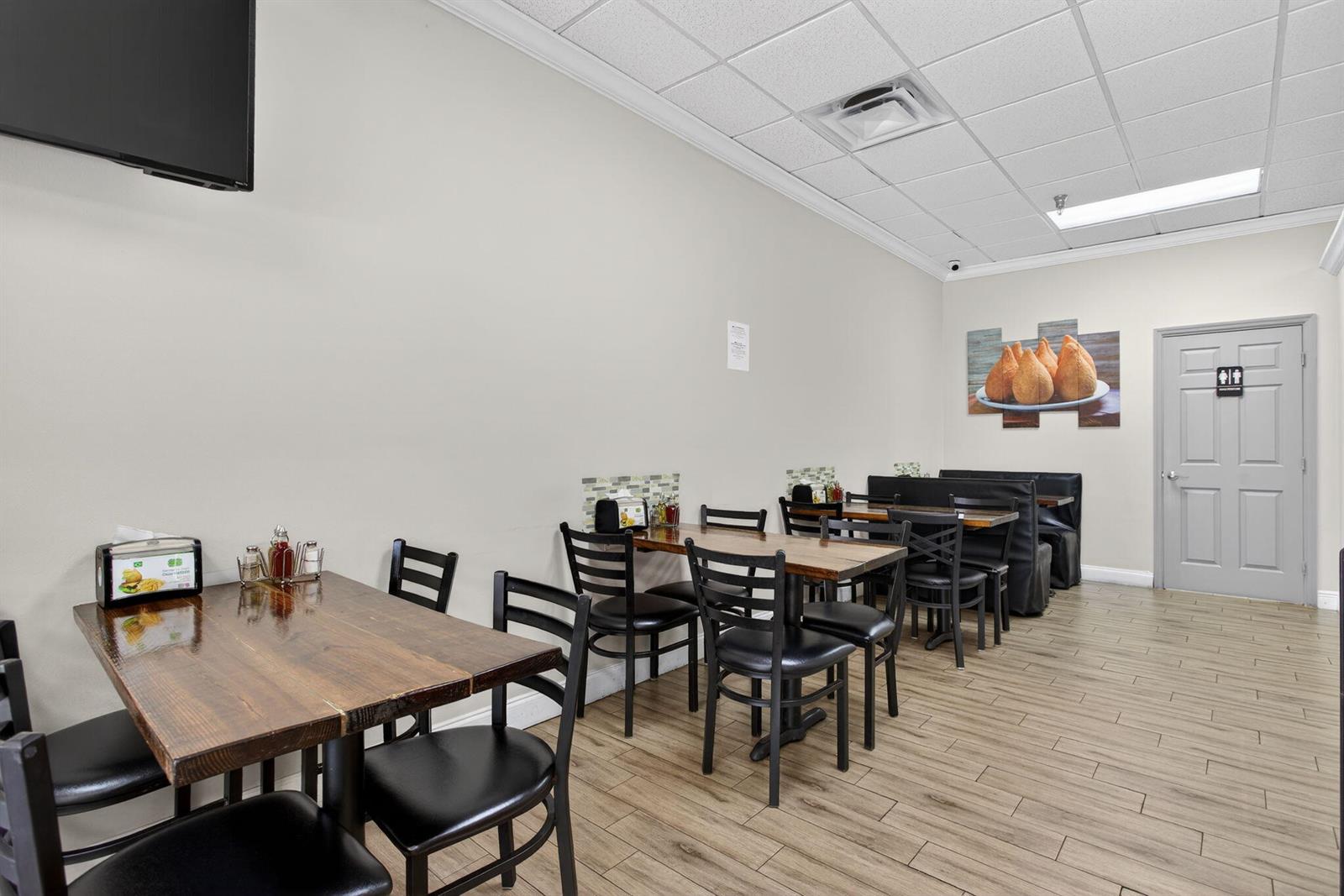 A restaurant dining area features wooden tables, black chairs, and a restroom door — Null W Null, Coconut Creek FL 33073, COCONUT CREEK, FL