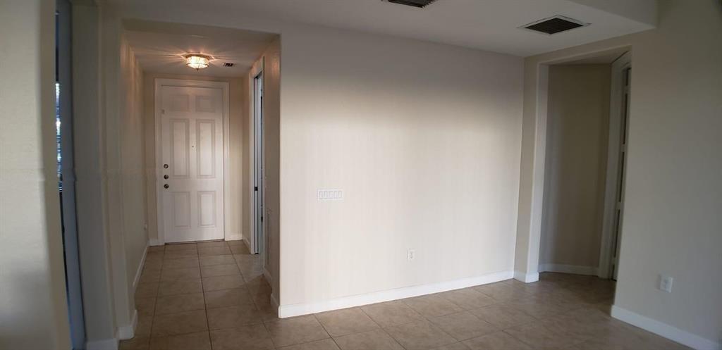 A view of a tiled entryway and hallway leading to a white front door — 8207 NW 128th Lane # b, Parkland FL 33076, PARKLAND, FL