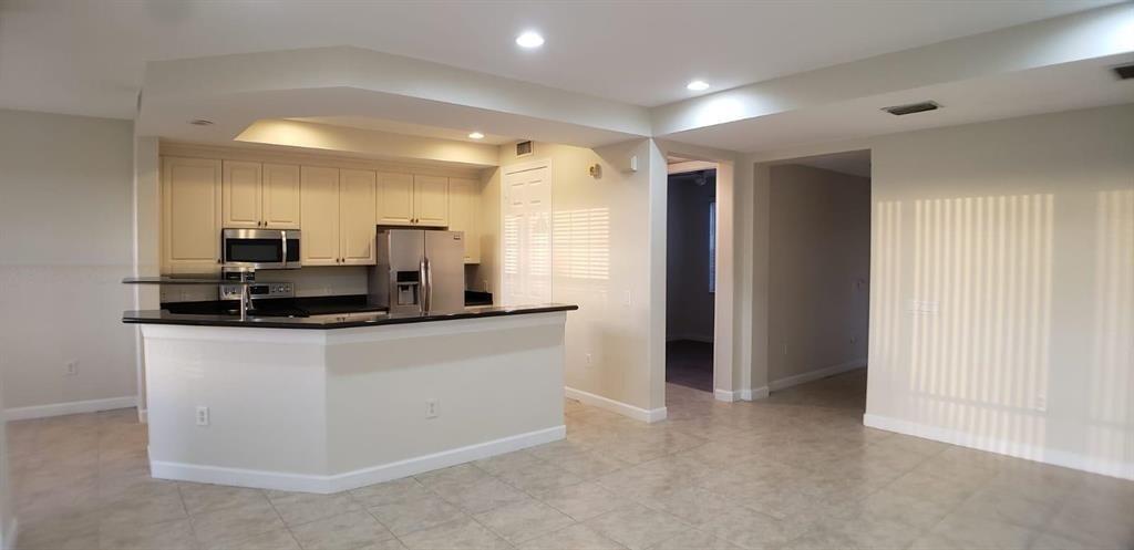 A kitchen with light-colored cabinets, stainless steel appliances, and a breakfast bar island — 8207 NW 128th Lane # b, Parkland FL 33076, PARKLAND, FL