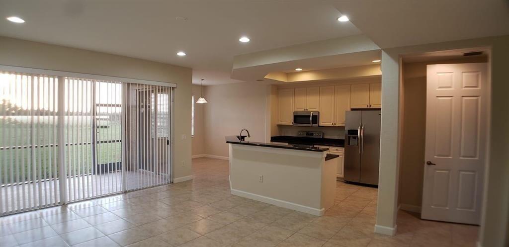 An open-concept kitchen with stainless steel appliances, a breakfast bar, and tile flooring — 8207 NW 128th Lane # b, Parkland FL 33076, PARKLAND, FL