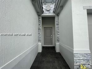 A narrow entryway features a gray front door, stone accents, and dark paver flooring — 863 SE 26th Ter # 0, Homestead FL 33035, HOMESTEAD, FL