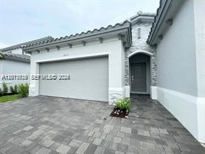 A light gray house exterior features a two-car garage and a stone-accented entryway — 863 SE 26th Ter # 0, Homestead FL 33035, HOMESTEAD, FL