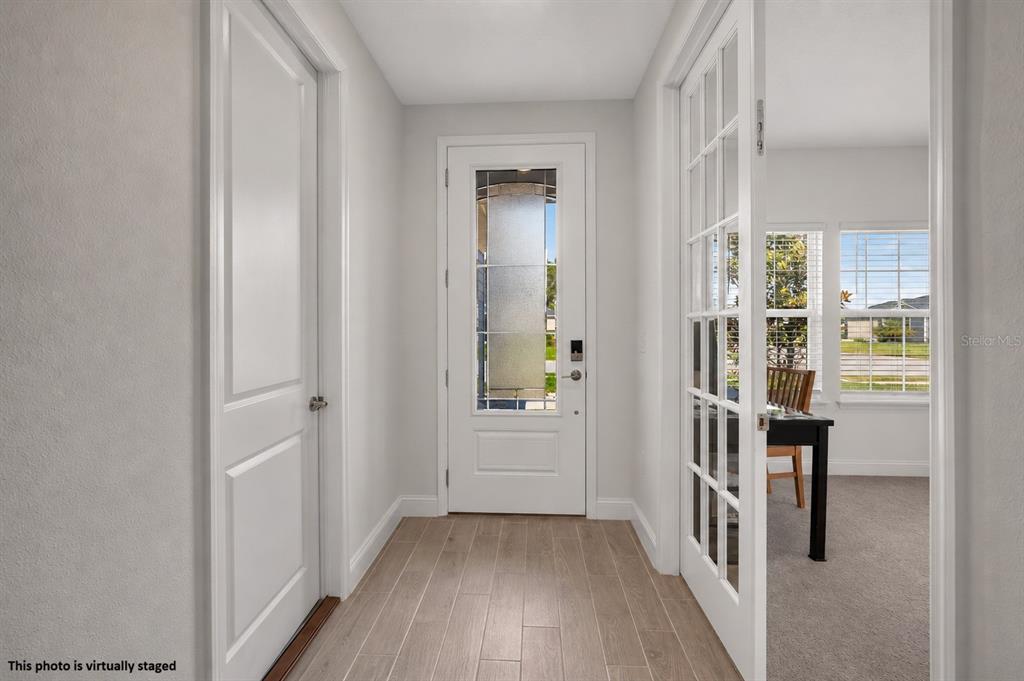 A bright entryway features light wood-look flooring, a white front door, and French doors — 2173 RAGLAN CIRCLE, ORMOND BEACH, FL